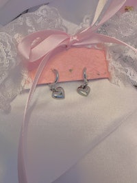 a pair of earrings with a pink ribbon