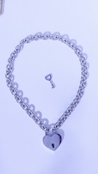 a silver chain with a key and a heart on it